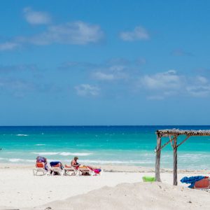 playa azul con tumbonas y personas tomando el sol en jardines del rey